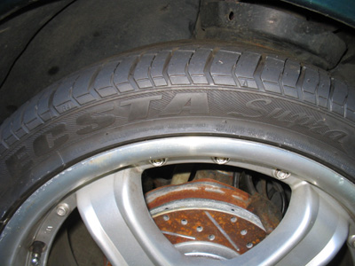 1995 Ford Taurus - A close-up view of a car's wheel, tire, and brake rotor, showing some wear on the rotor.