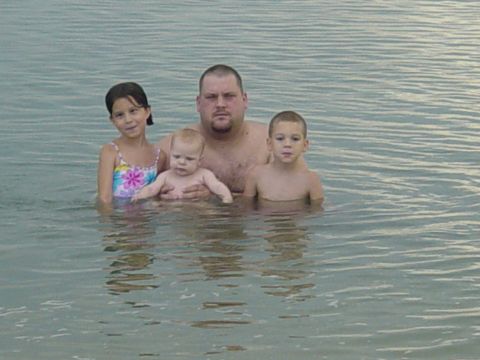 1989 Ford Bronco - A man and three children are in the water at a beach.