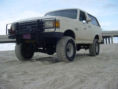 1989 Ford Bronco - This 1989 Ford Bronco is equipped with off-road tires and a brush guard, parked on a sandy beach.