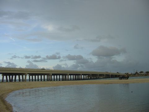 1989 Ford Bronco - SUV parked on beach near a bridge.