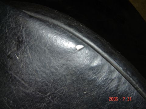 1993 Ford Bronco - Detail of a black leather seat showing wear and a small white debris piece.