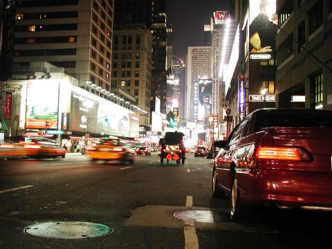 1992 Ford Taurus - A red sedan is parked on a busy city street at night, with blurred traffic in motion.