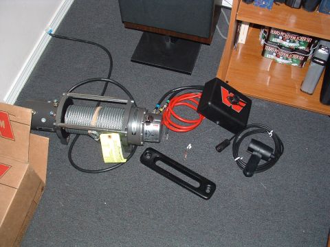 1993 Ford Bronco - A winch and its associated accessories are displayed on a carpeted floor.