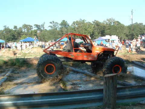1993 Ford Bronco - Custom off-road buggy tackles a challenging mud pit during an event.