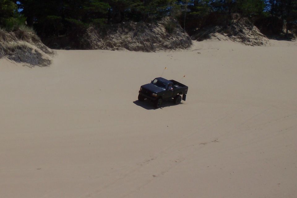 Black pickup truck on sand dunes, 3/4 front view