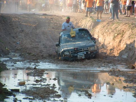1993 Ford Bronco - A truck is stuck in a muddy ditch while spectators watch from the bank.