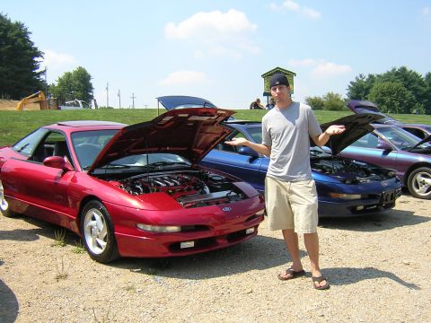 1995 Ford Probe - A man stands between several Ford Probes with their hoods open at an outdoor car show.