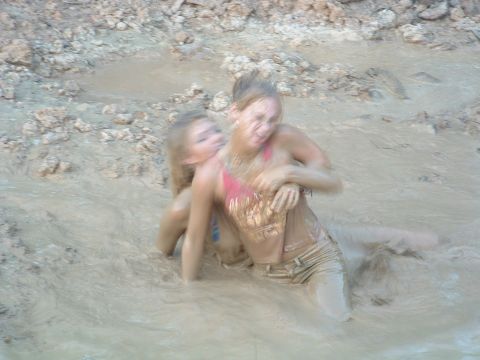 1993 Ford Bronco - Two individuals are engaged in a wrestling match within a muddy environment.