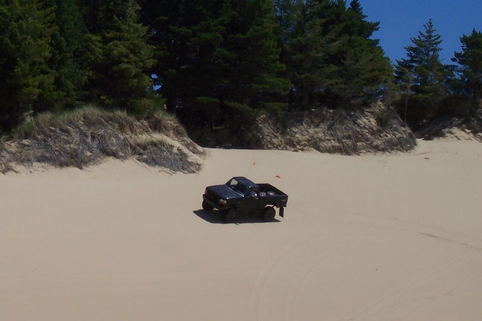 Dark blue pickup truck on sand dunes, 3/4 front view. Appears to be from the early 1990s
