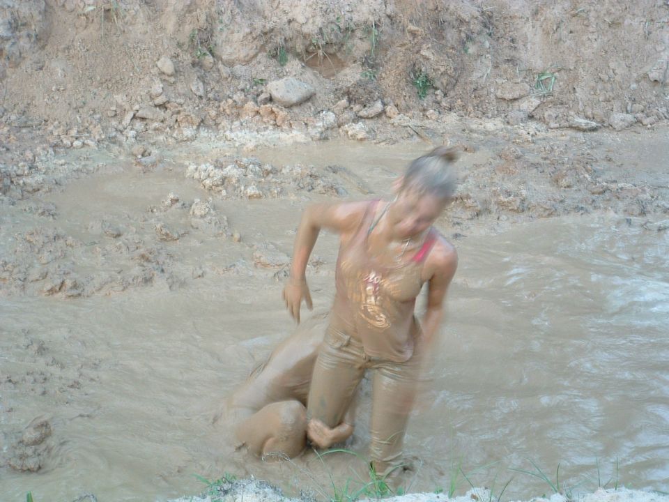 Person covered in mud struggling in a muddy ditch