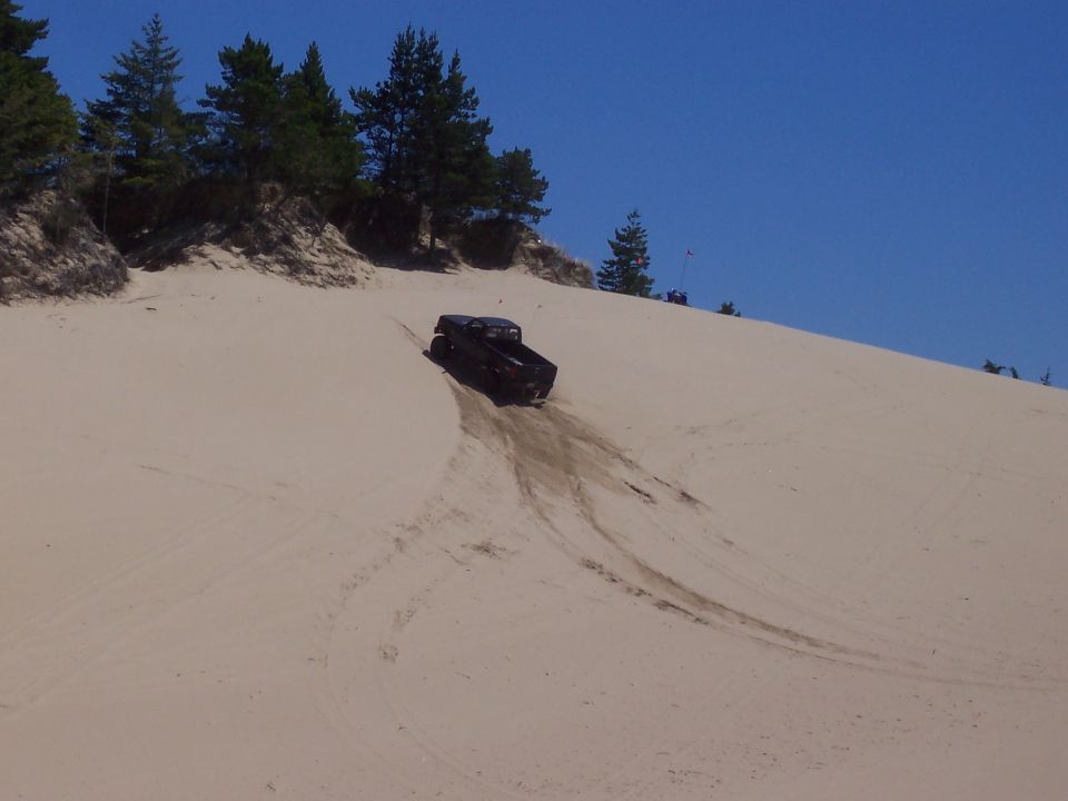 Black 1994 Ford F-150 driving down a sand dune
