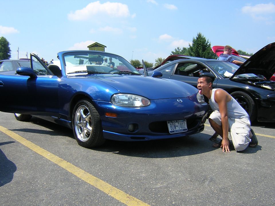Blue Mazda Miata convertible with open door, man posing in front