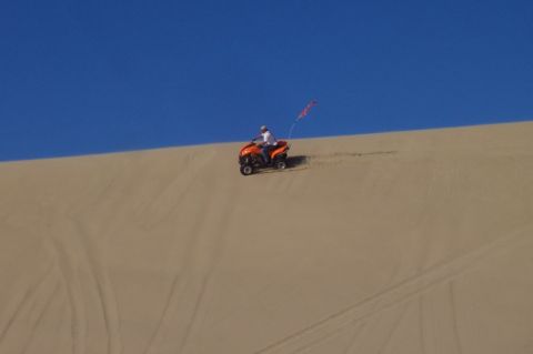 1994 Ford F-150 - An ATV rider navigates a sandy slope, a colorful flag trailing behind.