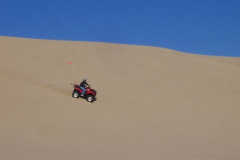 1994 Ford F-150 - A person rides a red ATV down a sandy slope under a clear blue sky.