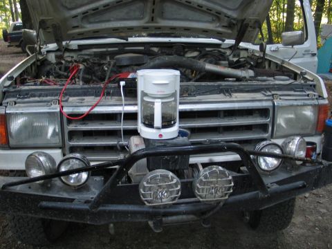 1995 Ford Bronco - White pickup truck with hood open and coffee maker on the grille, parked outdoors.