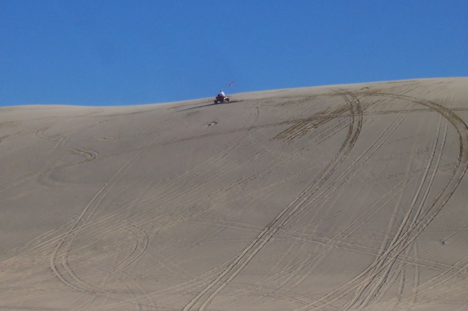 ATV on a sand dune with tire tracks