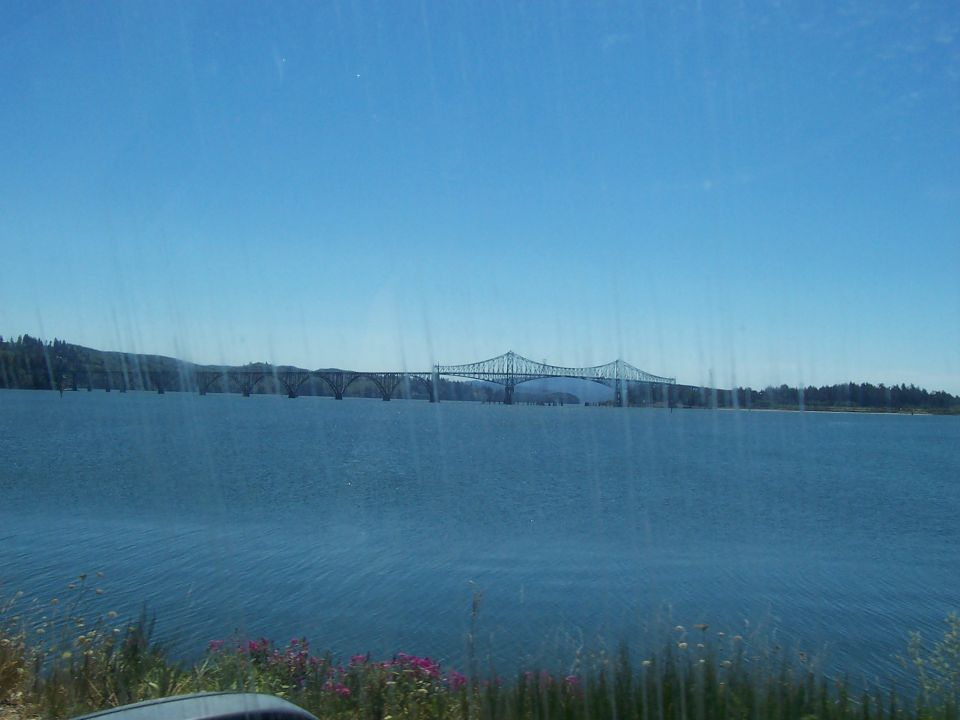 Long bridge spans a wide body of water under a clear blue sky