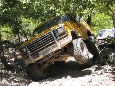 1995 Ford Bronco - This yellow SUV is tackling a challenging off-road course with steep inclines and rocky terrain.