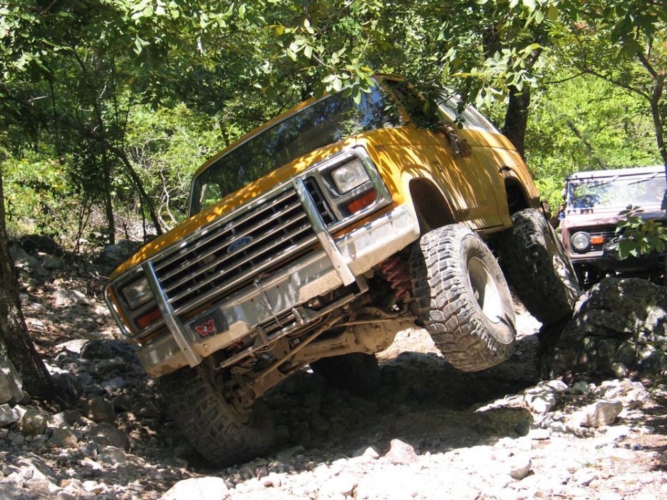 Yellow SUV with large tires navigating a rocky trail, another SUV behind it