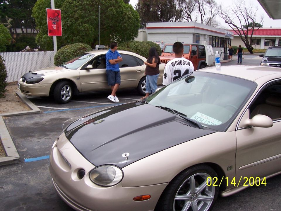 Gold sedan with black hood, parked next to an orange Jeep and another sedan
