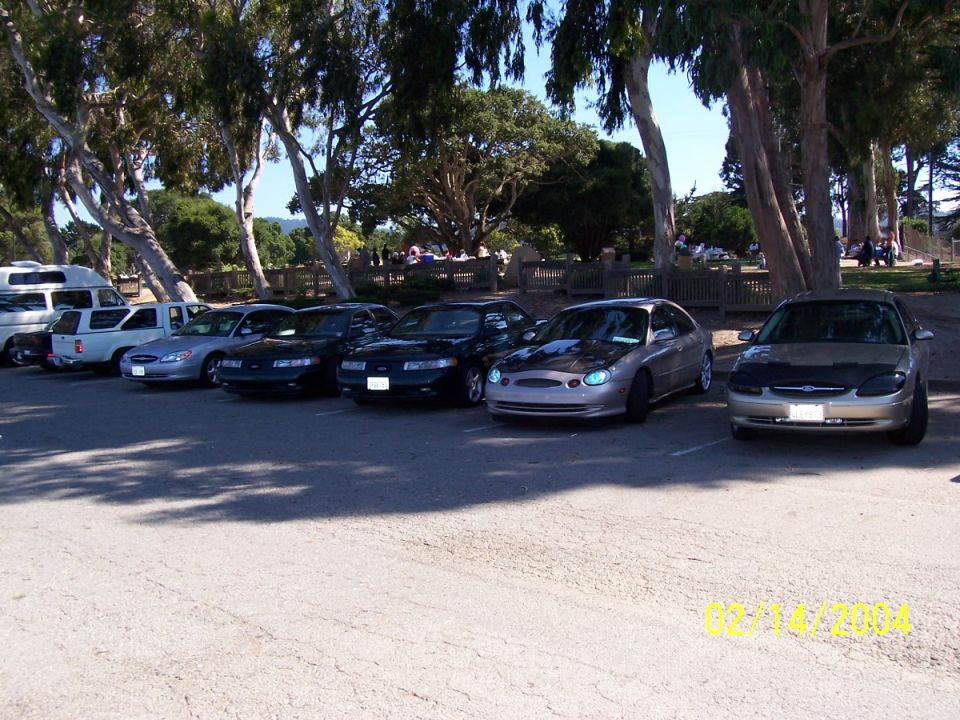 Silver sedan with aftermarket headlights and hood scoop, parked in a lot