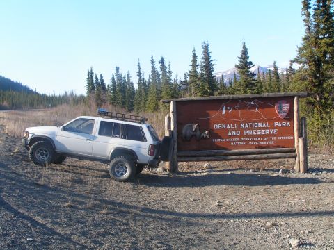 1995 Nissan Pathfinder - A white 1995 Nissan Pathfinder is parked next to the Denali National Park and Preserve sign.