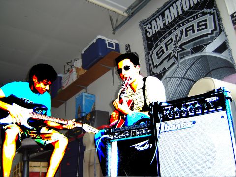 1988 Ford LTD Crown Victoria - Two musicians practice their guitars in a garage setting, with a San Antonio Spurs banner visible in the background.