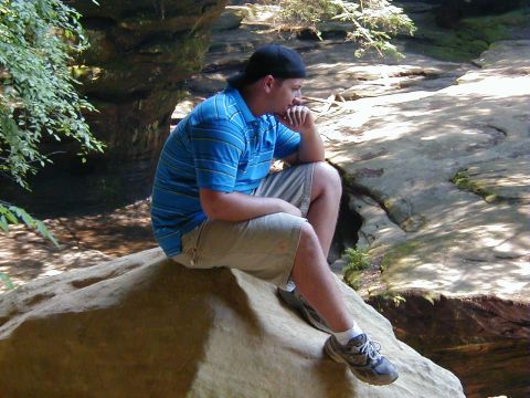 1994 Ford Probe - Man contemplates nature while seated on a large rock formation in an outdoor setting.