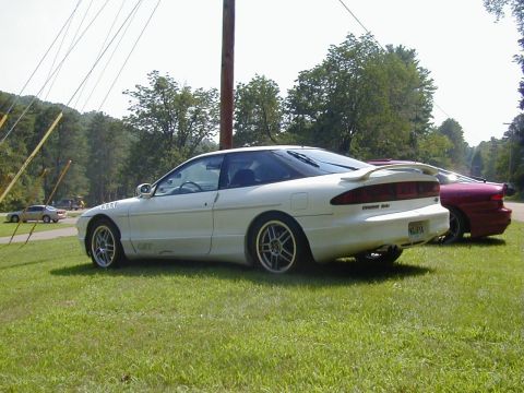 1994 Ford Probe - Two cars, a white 1994 Ford Probe and a red car, are parked on a grassy area.