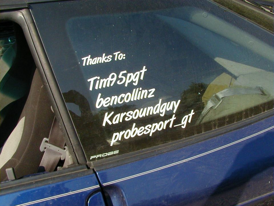 Side view of a blue car window with white stickers listing names and 'probesport_gt'. A small 'PROBE' badge is visible
