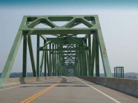 1994 Ford Probe - View from a vehicle crossing a large green truss bridge under a clear sky.