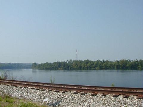1994 Ford Probe - A wide river or lake is bordered by trees, with railroad tracks in the foreground under a clear sky.