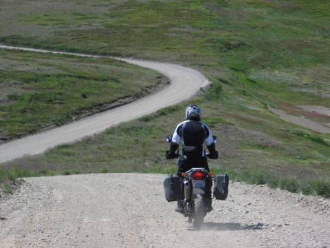 1997 BMW F650 - Riding a motorcycle on a gravel road through a scenic, hilly landscape.
