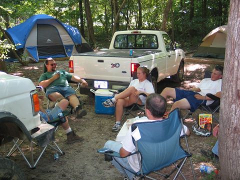 1995 Ford Bronco - People relax at a campsite next to a white pickup truck and tents.