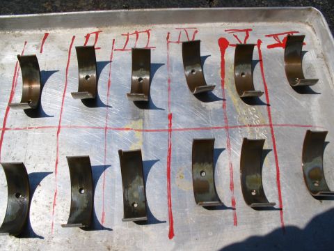1993 Ford Taurus - Engine rod bearings are arranged on a metal tray, marked with red lines and paint.