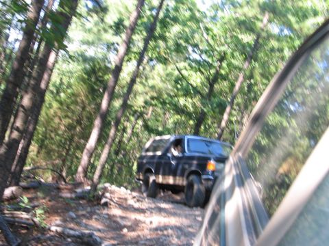 1995 Ford Bronco - A 1995 Ford Bronco navigates a rocky, wooded trail during an off-road event.