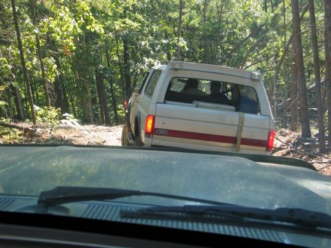1995 Ford Bronco - White Ford Bronco navigates a wooded trail during an off-road event.