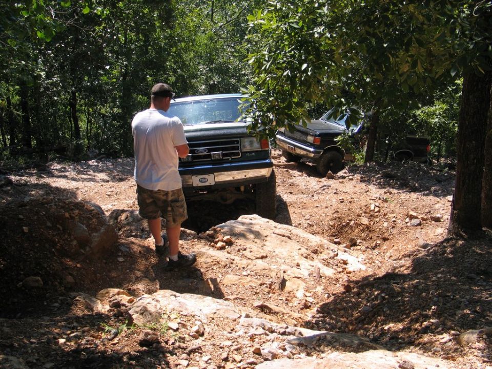 Dark green 1995 Ford Bronco on an off-road trail with another vehicle behind it