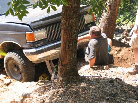 1995 Ford Bronco - A man attempts to free a stuck Ford F-Series truck from a wooded trail.