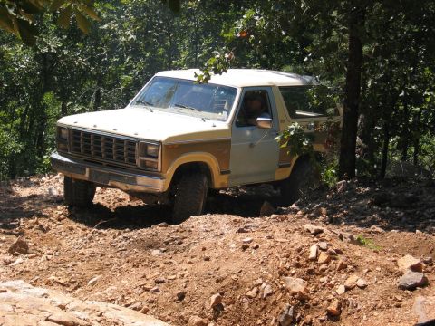 1995 Ford Bronco - A vintage Ford Bronco navigates a rocky, wooded path.