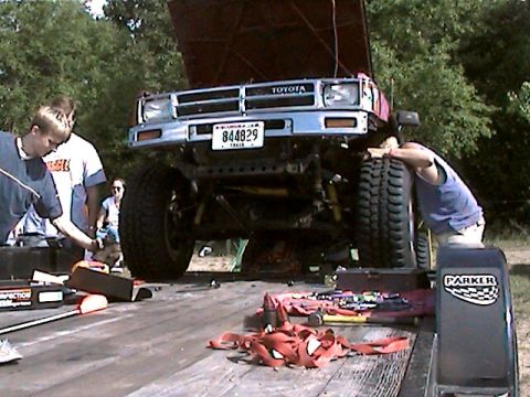 1977 Ford F-150 - A lifted Toyota truck is being worked on, with its hood open and tools scattered on the trailer.