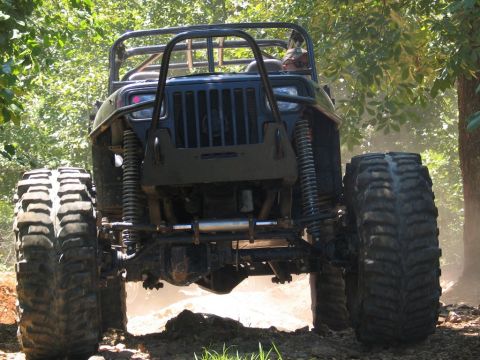 1995 Ford Bronco - This heavily modified off-road vehicle navigates a dusty trail, its extreme suspension and large tires.