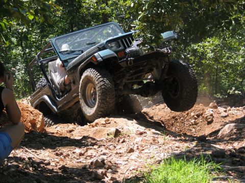 1995 Ford Bronco - Jeep Wrangler navigates a challenging off-road obstacle course with steep inclines and rocks.