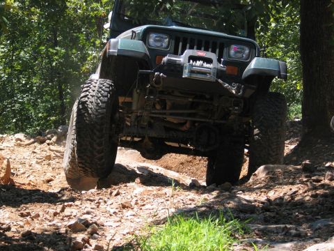 1995 Ford Bronco - A Jeep Wrangler navigates a rocky off-road trail, demonstrating its suspension and tire grip.