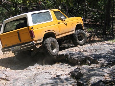 1995 Ford Bronco - This modified SUV navigates a challenging rocky terrain, demonstrating its off-road capabilities.