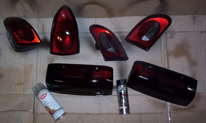 Six smoked/tinted tail light lenses drying on cardboard with Krylon clear coat and Nite Shades tint spray cans.
