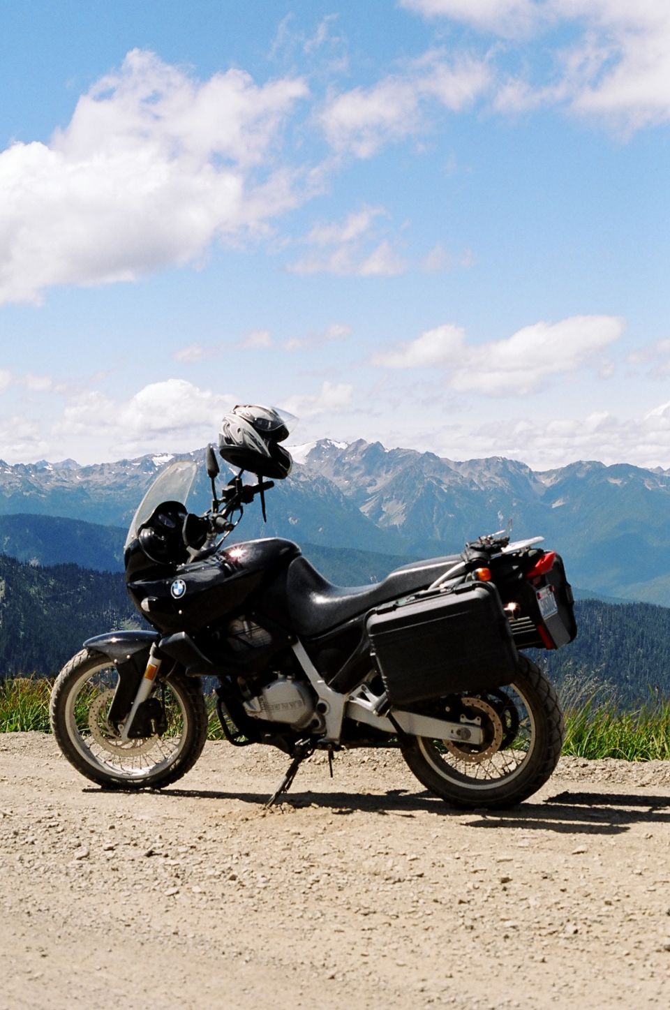 Black BMW dual-sport motorcycle parked on gravel with mountains behind