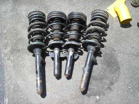 1991 Ford Taurus - A set of four used shock absorbers are displayed on a concrete surface, with a yellow funnel in the background.