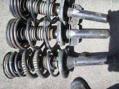 1991 Ford Taurus - A trio of automotive suspension struts are displayed, showing their coiled springs and mounting hardware.