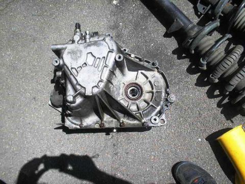 1991 Ford Taurus - Transmission and suspension components are laid out on a paved surface.